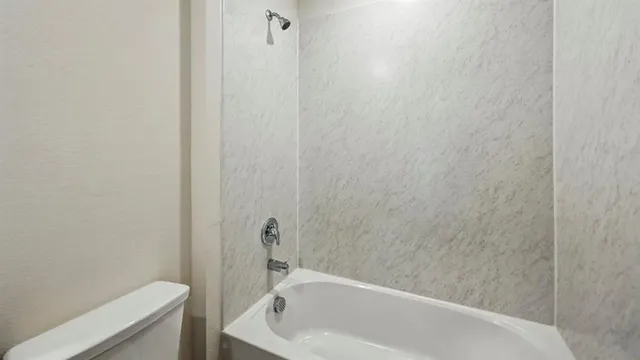 a bathroom with a white bath tub and a toilet