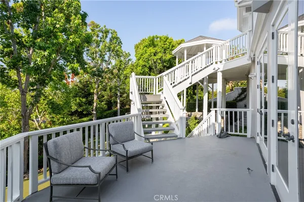 a view of a white house with a yard plants and large tree