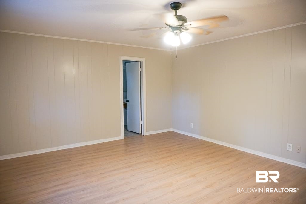 6205 Zeigler Boulevard Mobile, AL 36608 - Photo 12 of 17 Unfurnished room featuring light wood-style flooring, crown molding, wood walls, and ceiling fan