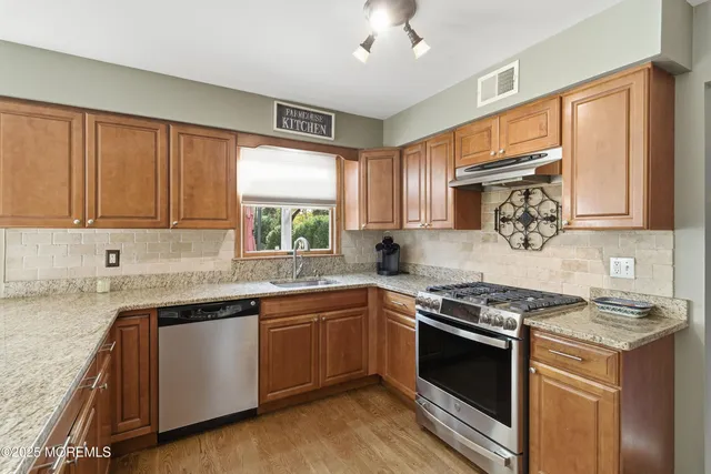 a kitchen with stainless steel appliances granite countertop a stove sink and cabinets