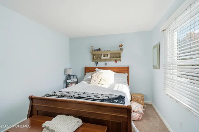 a bed sitting in a bedroom next to a window with a lamp and a window
