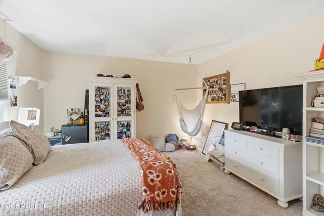 a bedroom with bed and a flat tv screen on dresser