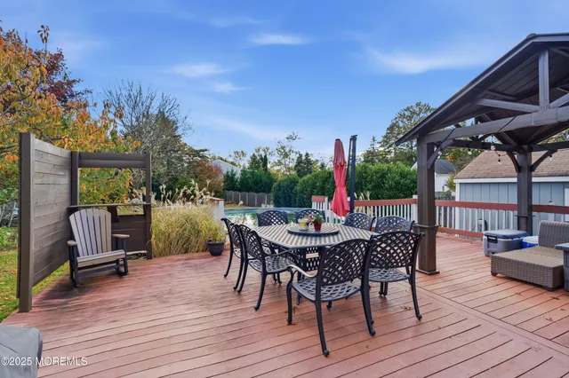 a view of a patio with a dining table and chairs with wooden floor and fence