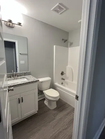 a bathroom with a granite countertop toilet a sink and a mirror