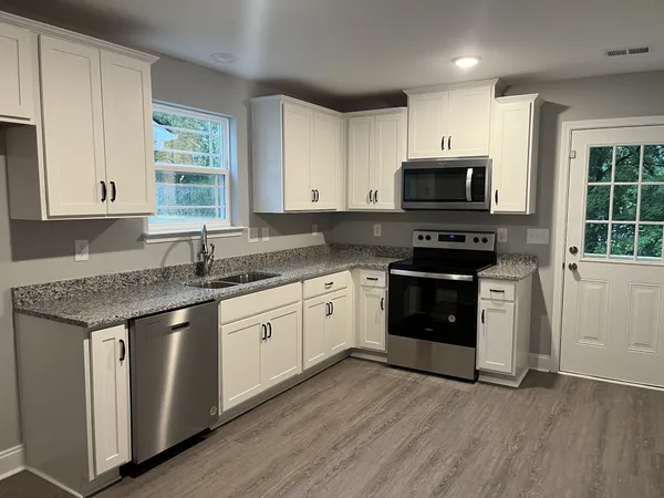 a kitchen with stainless steel appliances granite countertop a stove a sink and a microwave