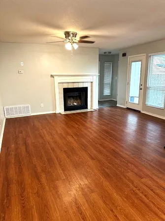an empty room with wooden floor fireplace and windows