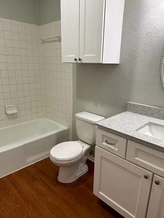 a bathroom with a granite countertop toilet sink and mirror