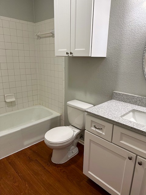 371 Fantail Loop, Unit B Austin, TX 78734 - Photo 5 of 10 Bathroom featuring a textured wall, vanity, dark wood-style flooring, and shower / bath combination