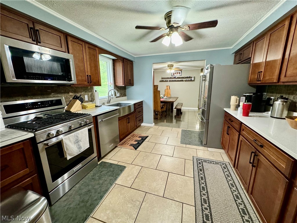 86 Cunningham Hill Road Harrisville, WV 26362 - Photo 10 of 32 Kitchen featuring stainless steel appliances, sink, light tile patterned floors, decorative backsplash, and ceiling fan