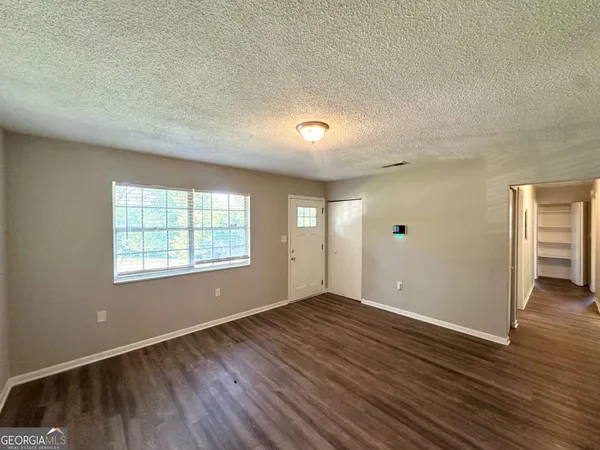 an empty room with wooden floor and windows