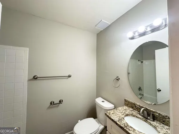 a bathroom with a granite countertop toilet sink and mirror