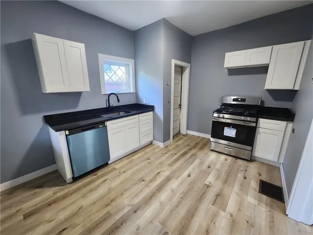 a kitchen with granite countertop a stove a sink and a refrigerator