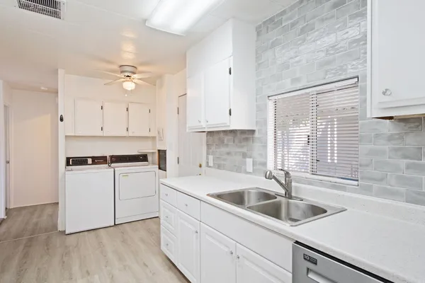 a kitchen with refrigerator a stove a sink and white cabinets