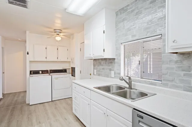 a kitchen with refrigerator a stove a sink and white cabinets