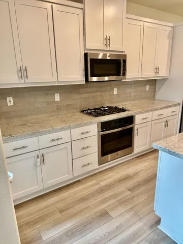 a kitchen with granite countertop a stove a microwave a sink and cabinets