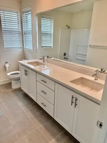 a bathroom with a double vanity sink a toilet and a tub