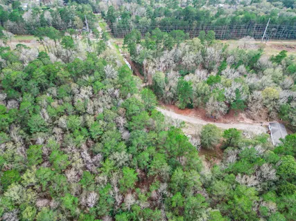 an aerial view of residential house with outdoor space and trees all around
