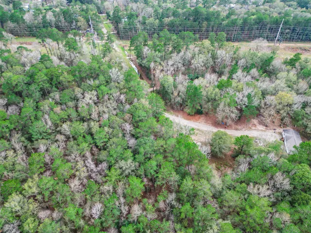 an aerial view of residential house with outdoor space and trees all around