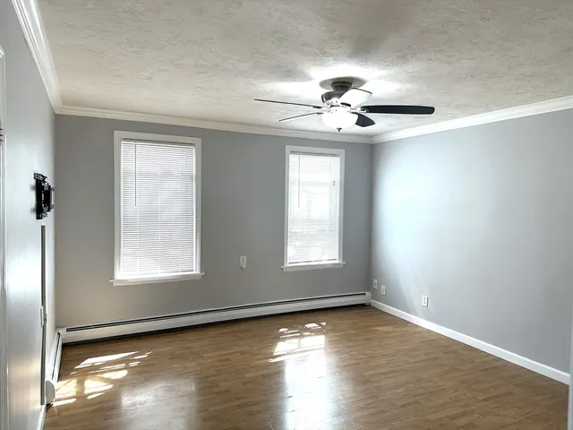 an empty room with wooden floor chandelier fan and windows