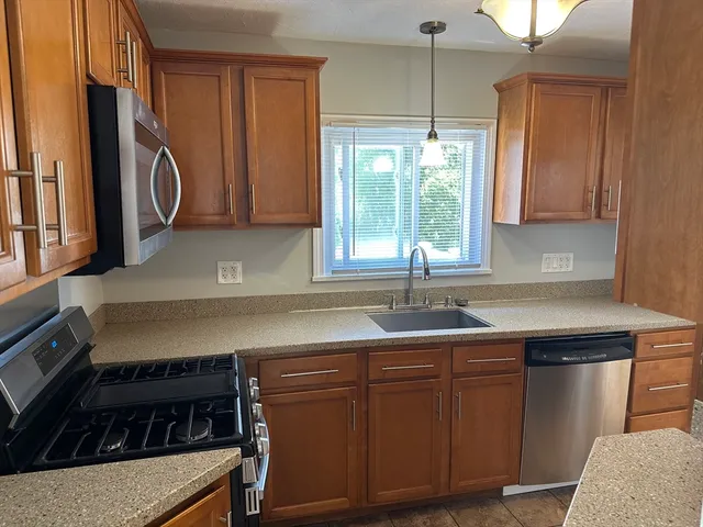 a kitchen with granite countertop a sink a stove and cabinets