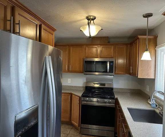 a kitchen with stainless steel appliances granite countertop a refrigerator a stove and a sink