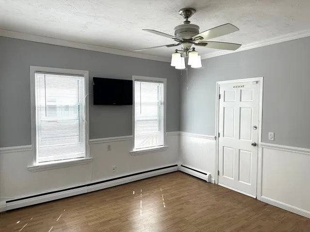 an empty room with wooden floor fan and windows