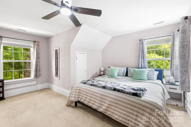 a bedroom with a bed next to a window and a chandelier
