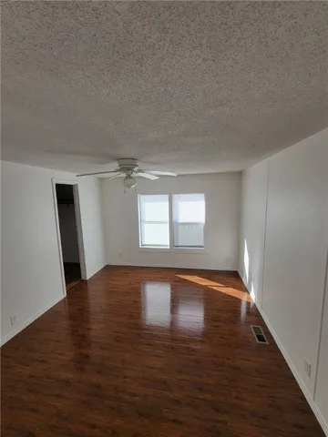 a view of an empty room with window and wooden floor