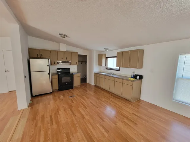a large kitchen with cabinets wooden floor and stainless steel appliances