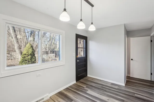 a view of an empty room with a window and wooden floor