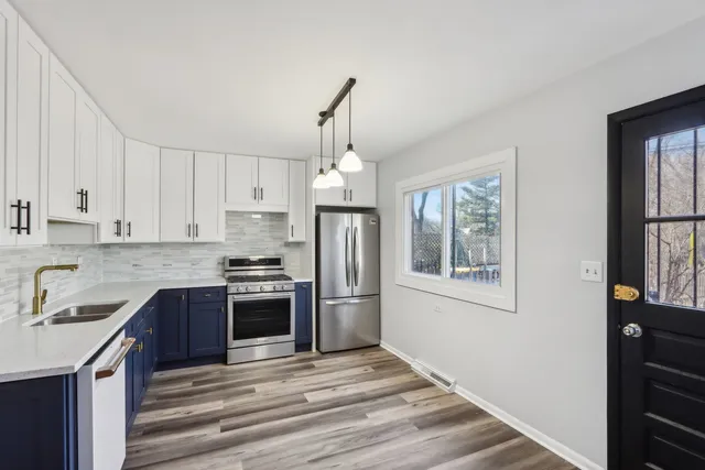 a kitchen with stainless steel appliances granite countertop a refrigerator a stove a sink dishwasher and a refrigerator with wooden floor