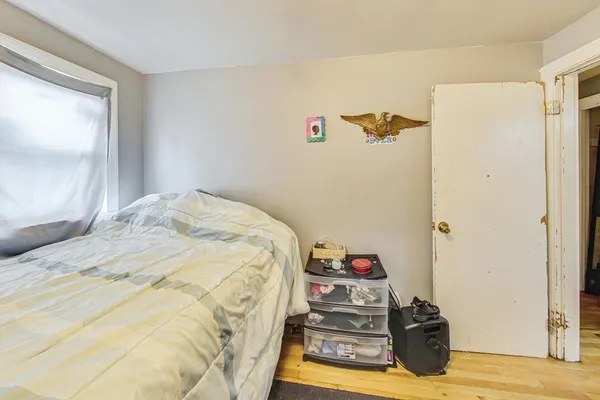 a bedroom with a bed and a dresser with wooden floor