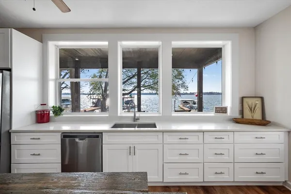 a kitchen with granite countertop a sink window and cabinets
