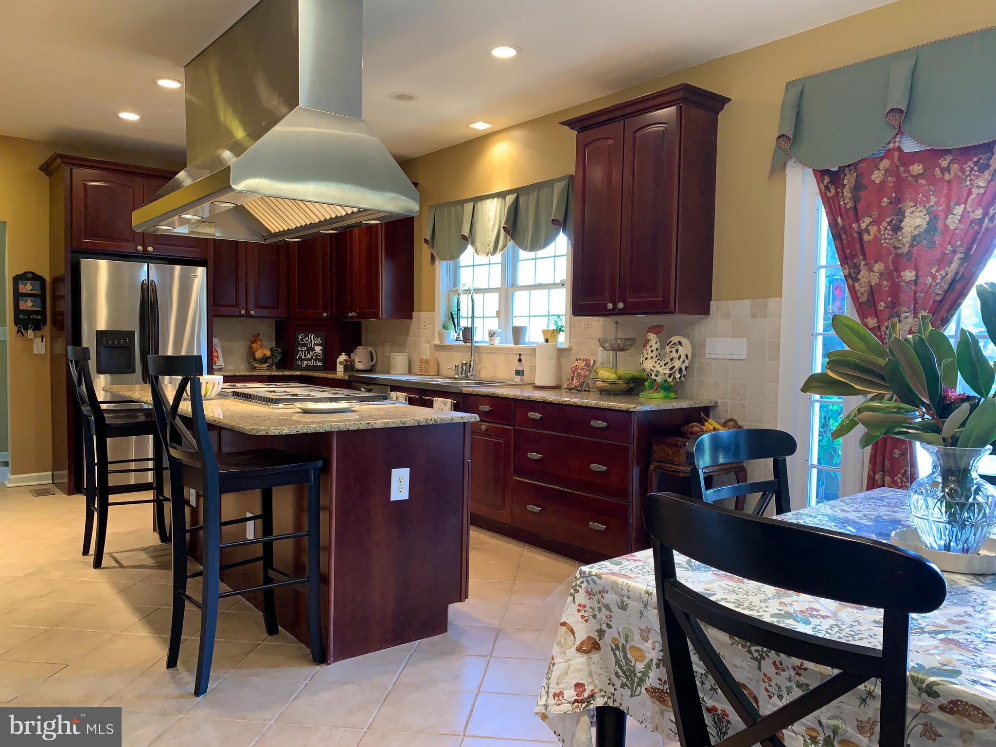 163 Sharon Station Road Robbinsville, NJ 08691 - Photo 17 of 38 a kitchen with stainless steel appliances kitchen island granite countertop a table chairs in it and wooden floors