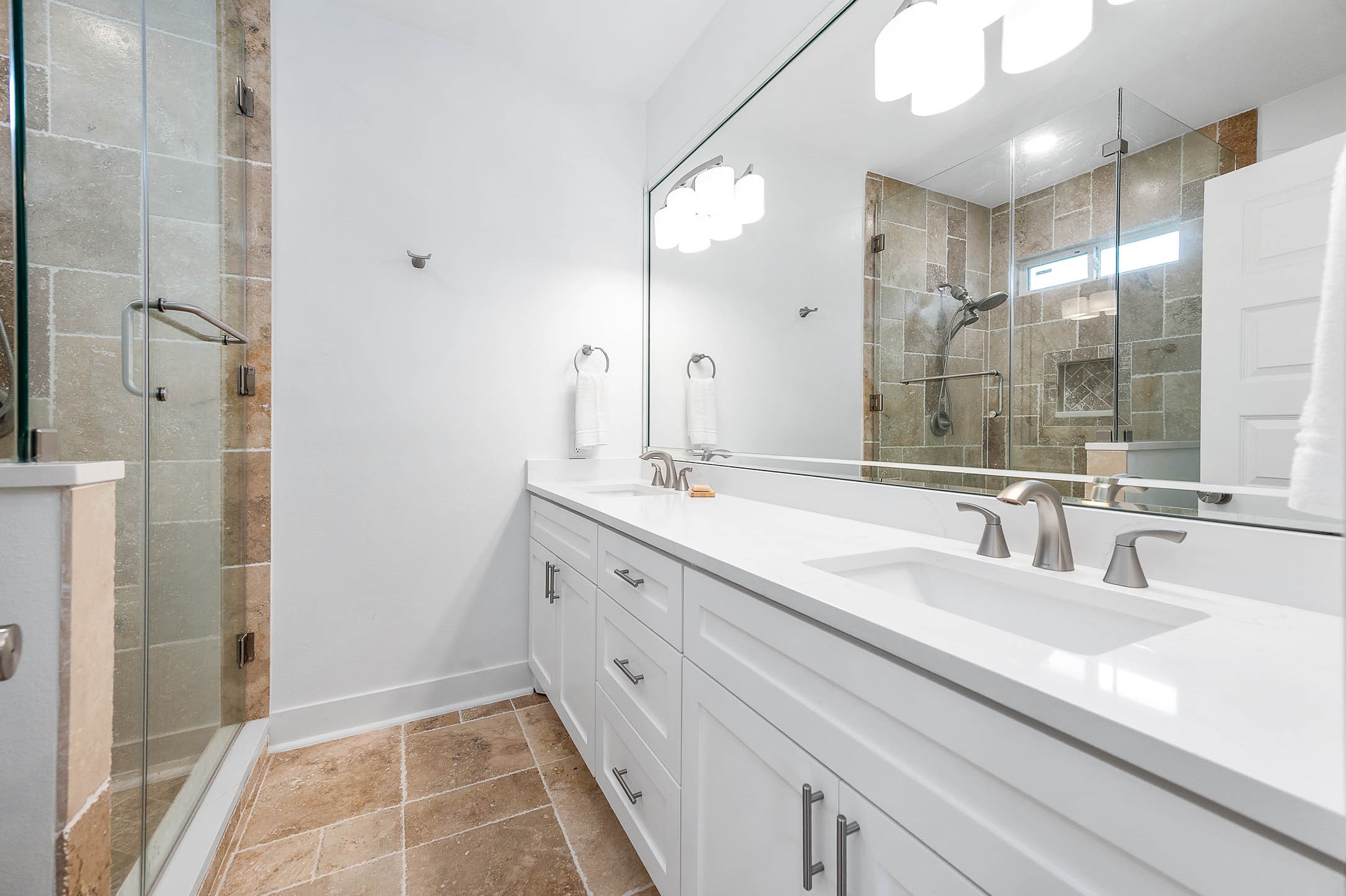 8032 Short Road Needville, TX 77461 - Photo 19 of 50 The primary bathroom offers a spacious and modern design featuring dual sinks, expansive counter space, and sleek white cabinetry. A beautifully tiled glass-enclosed shower adds a touch of luxury while creating a clean and elegant atmosphere.