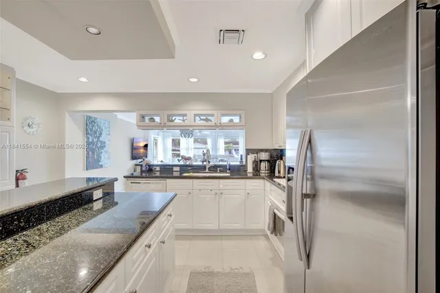 a large kitchen with kitchen island a large counter top space a sink appliances and cabinets