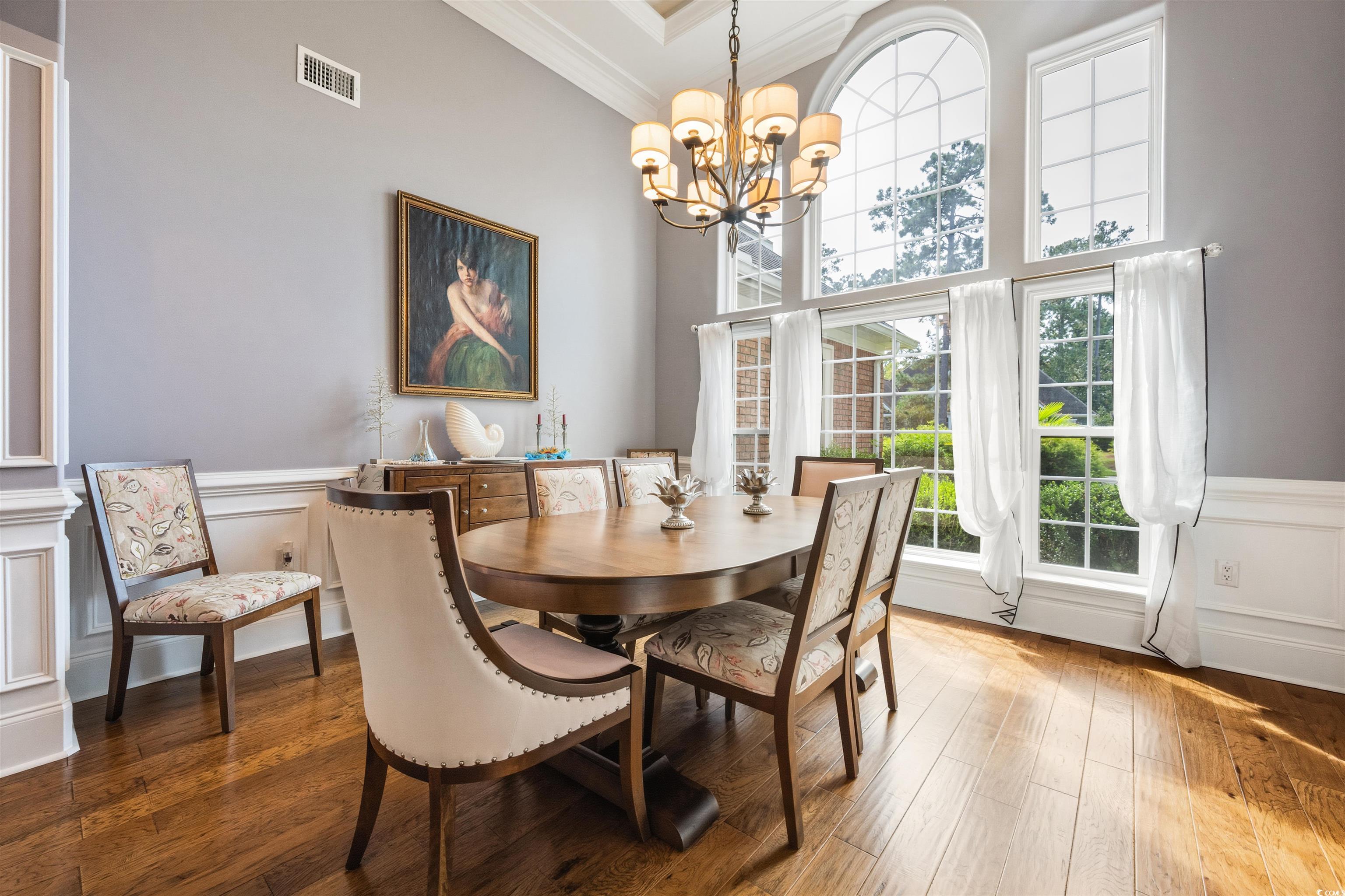 2073 Timmerman Road Myrtle Beach, SC 29588 - Photo 4 of 34 Dining area featuring a wainscoted wall, crown molding, wood finished floors, and a chandelier