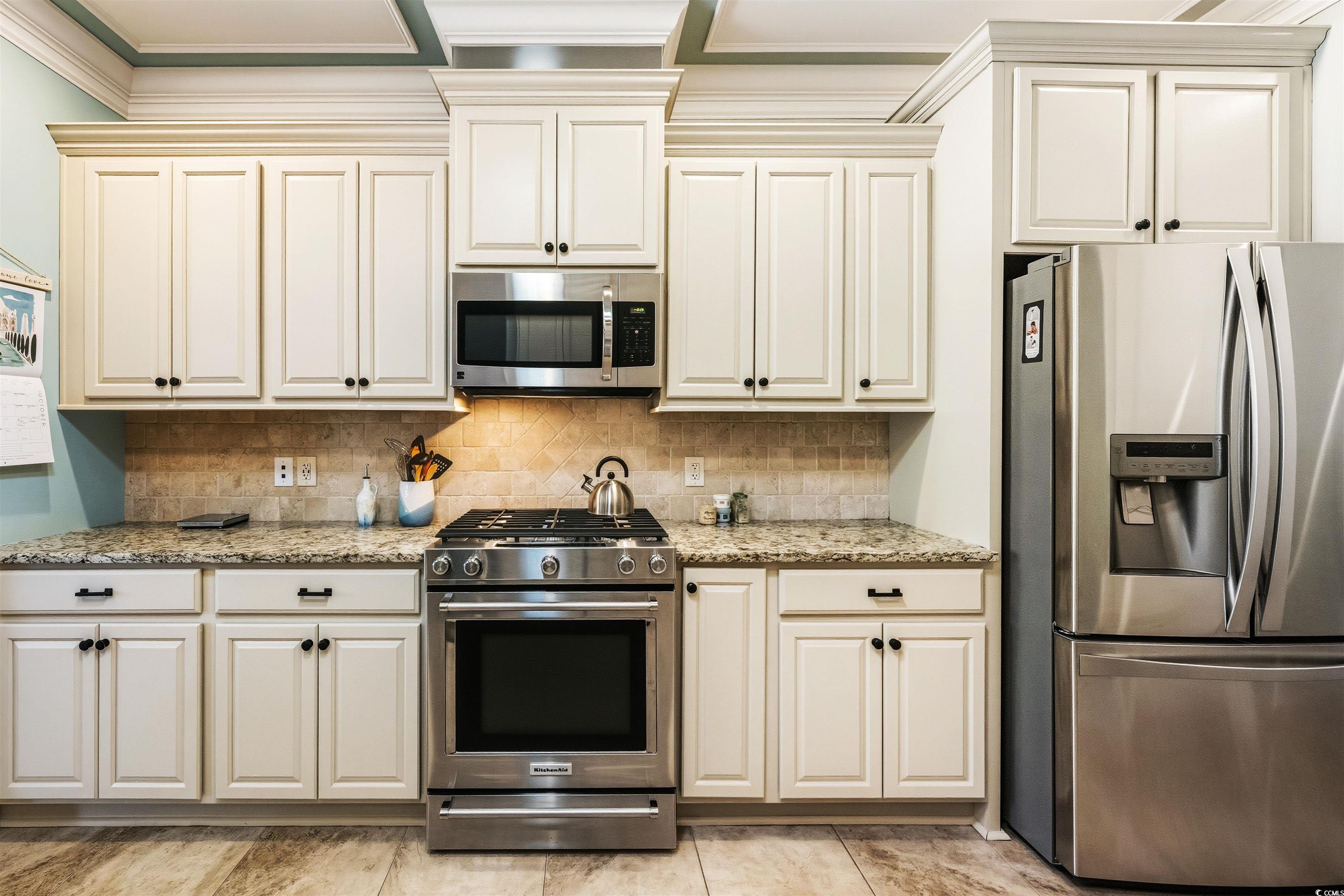 2073 Timmerman Road Myrtle Beach, SC 29588 - Photo 7 of 34 Kitchen with stainless steel appliances, tasteful backsplash, light stone countertops, and cream cabinetry