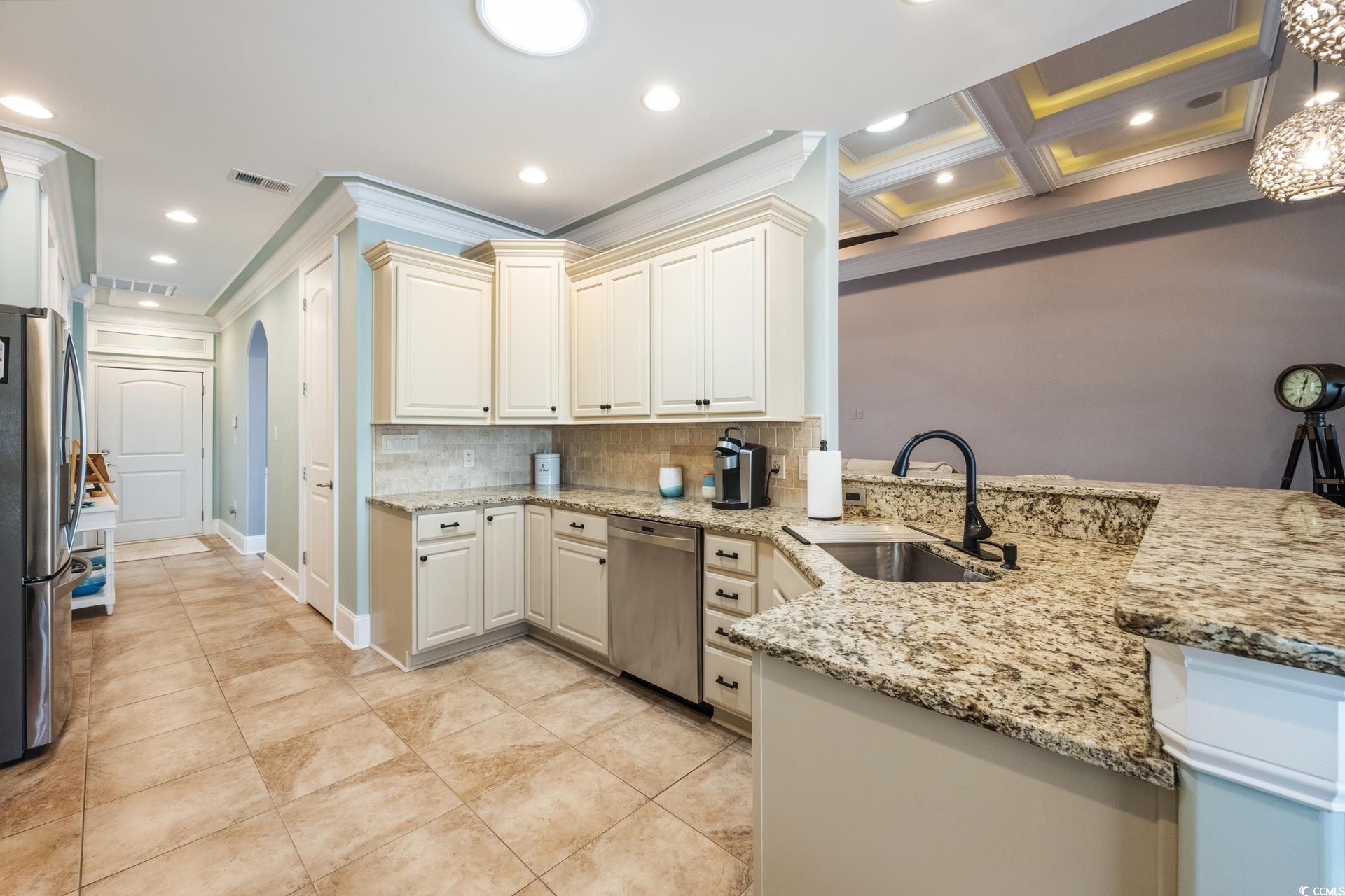 2073 Timmerman Road Myrtle Beach, SC 29588 - Photo 8 of 34 Kitchen featuring light stone counters, appliances with stainless steel finishes, decorative backsplash, a peninsula, and ornamental molding