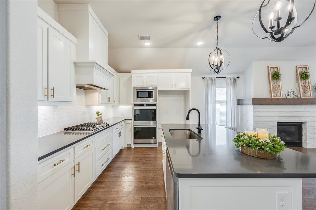 a kitchen with stainless steel appliances granite countertop a sink a stove and a wooden floors