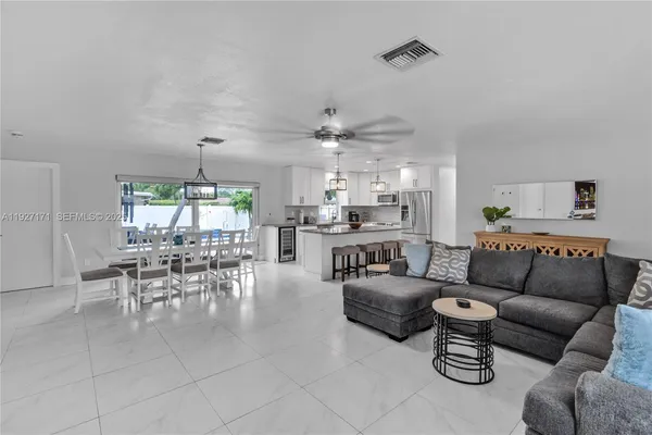 a living room with furniture kitchen area and a chandelier