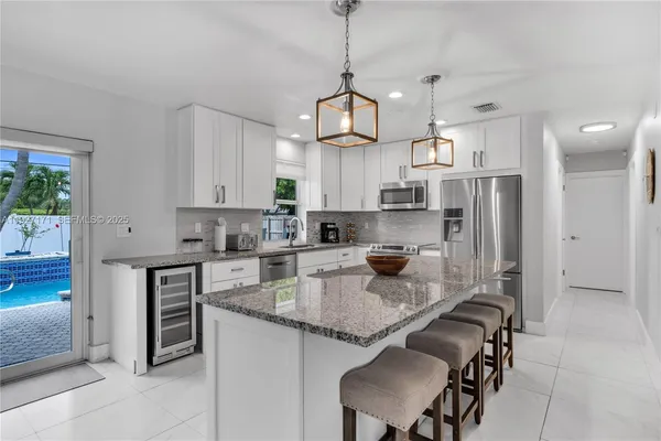 a kitchen with stainless steel appliances granite countertop a sink a stove a refrigerator cabinets and chairs