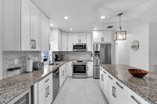 a large kitchen with stainless steel appliances granite countertop a sink stove and refrigerator
