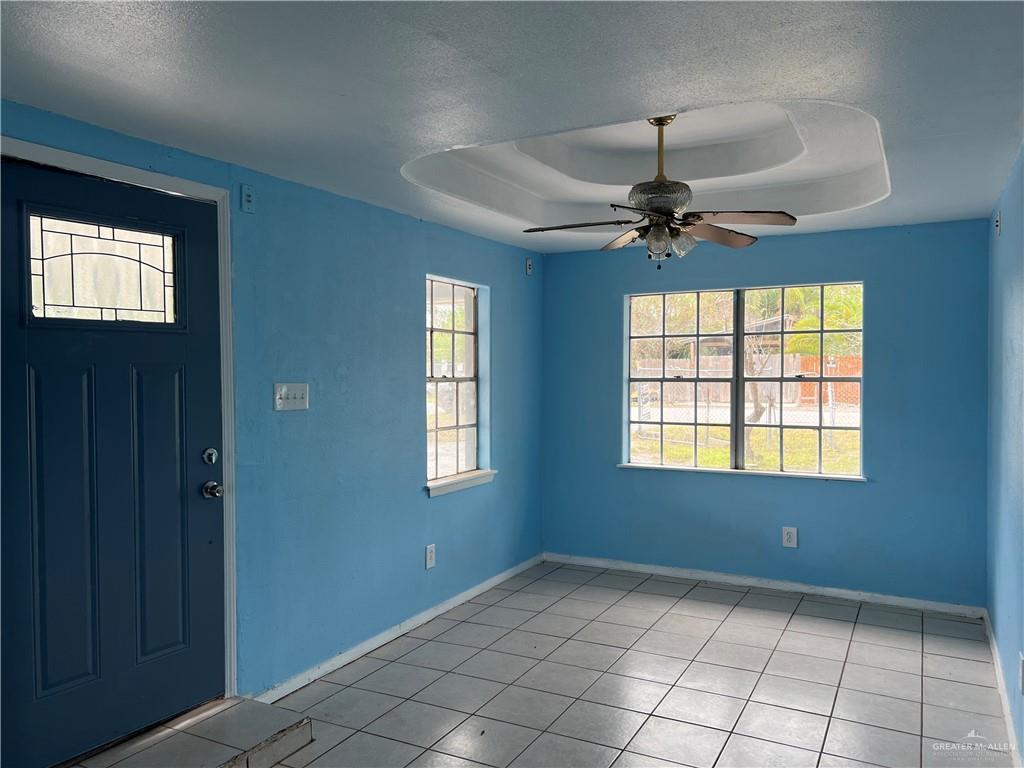 1015 Martinez Street Weslaco, TX 78596 - Photo 2 of 10 Foyer entrance featuring a textured ceiling, a ceiling fan, a raised ceiling, and light tile patterned flooring