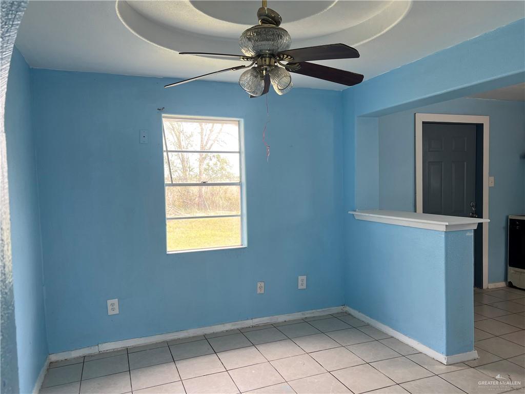 1015 Martinez Street Weslaco, TX 78596 - Photo 3 of 10 Empty room with a ceiling fan, light tile patterned floors, and a raised ceiling