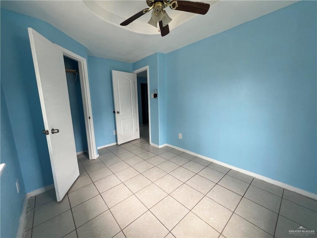 1015 Martinez Street Weslaco, TX 78596 - Photo 5 of 10 Unfurnished bedroom with light tile patterned floors, ceiling fan, a raised ceiling, and a closet