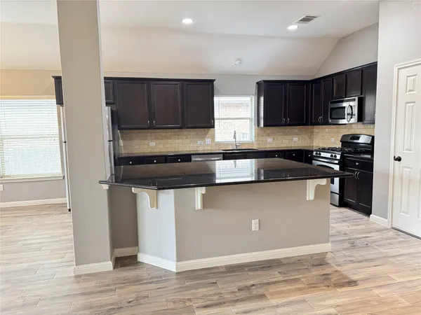 a kitchen with stainless steel appliances granite countertop a stove a sink and a refrigerator