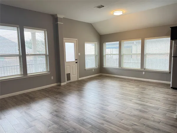 an empty room with wooden floor and windows