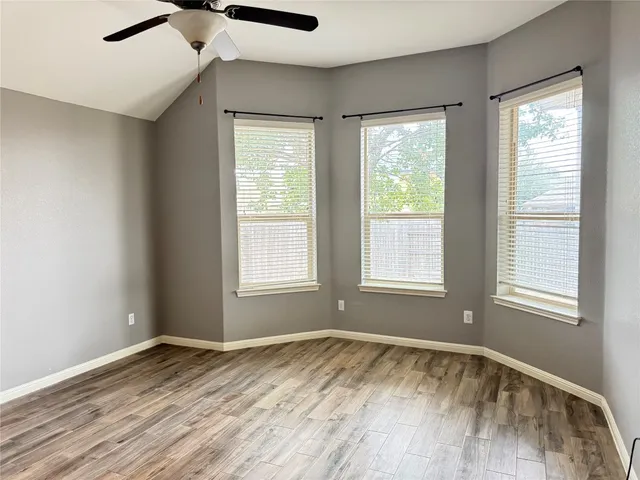 a view of empty room with wooden floor and fan