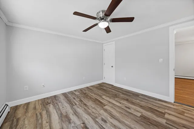 an empty room with wooden floor and ceiling fan